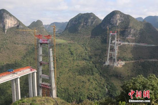 11月22日，正在建設(shè)中的峰林特大橋。當(dāng)日，隨著1470噸裝配化預(yù)制中橫梁提升到位，貴州省黔西南布依族苗族自治州興義環(huán)城高速公路峰林特大橋4號(hào)主塔中橫梁成功吊裝，由此刷新了山區(qū)峽谷橋梁預(yù)制吊裝混凝土構(gòu)件重量世界記錄。峰林特大橋是屬全線控制性工程。大橋跨越馬嶺河峽谷，全長(zhǎng)1163米，主跨采用550米懸索橋，橋面離谷底364.2米，是中國(guó)山區(qū)第一座大跨徑鋼混疊合梁懸索橋。中新社記者 瞿宏倫 攝